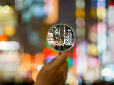 Image of a magnifying glass with a blurred cityscape in the background